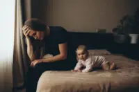 Upset mom with baby on the bed.